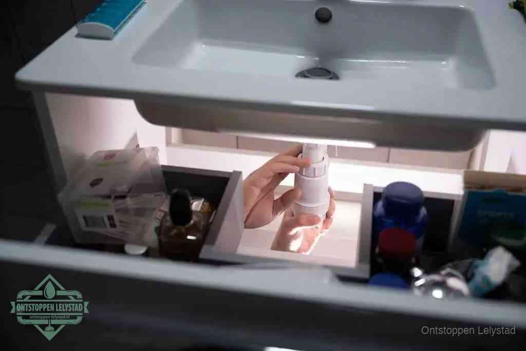 Een pompfles met zeep boven een wastafel, de heet water en afwasmiddel-methode om een vetprop in de afvoer los te maken in Lelystad