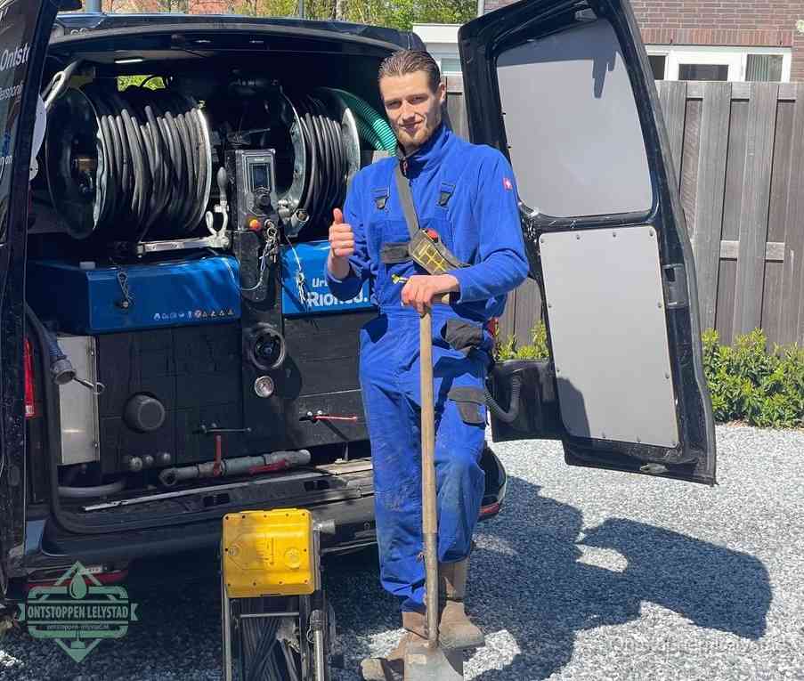 Een monteur bij de werkbus met grote hogedruk-slanghaspels, apparatuur voor hardnekkige afvoerverstoppingen in Lelystad