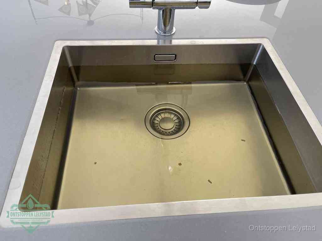 Stilstaand water in een rvs spoelbak dat niet wegloopt, een duidelijk signaal van een gootsteenverstopping in Lelystad