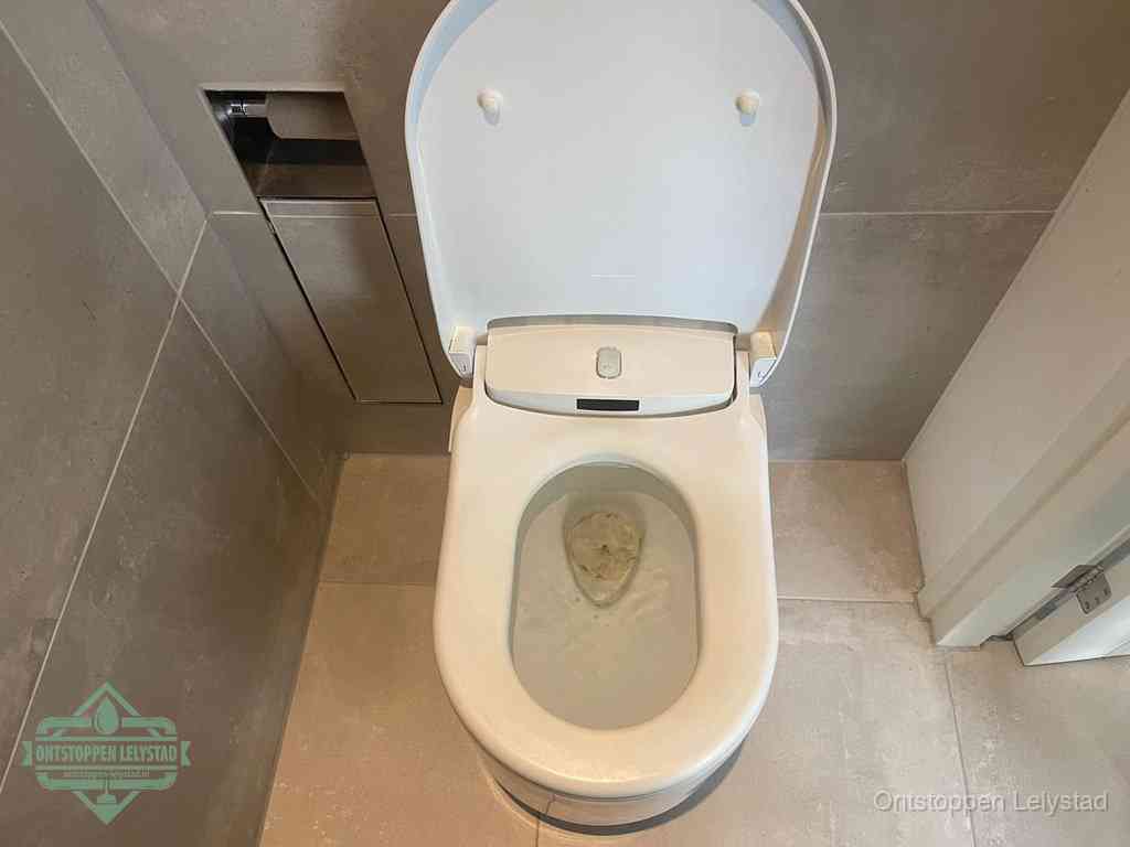 Een wit hangtoilet waarin een prop wc-papier op het water blijft drijven, een duidelijk signaal van een verstopte wc in Lelystad