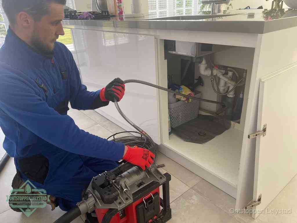 Een monteur reinigt de keukenafvoer grondig met een veermachine om terugkerende gootsteenverstoppingen te voorkomen in Lelystad