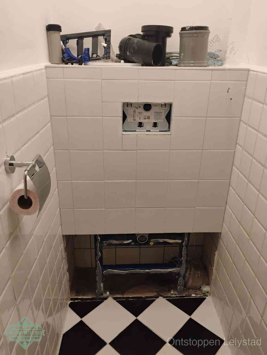 Een toiletruimte waar het hangtoilet en de inbouwreservoir-onderdelen zijn vrijgelegd voor onderhoud, periodiek nazicht voorkomt een wc-verstopping in Lelystad